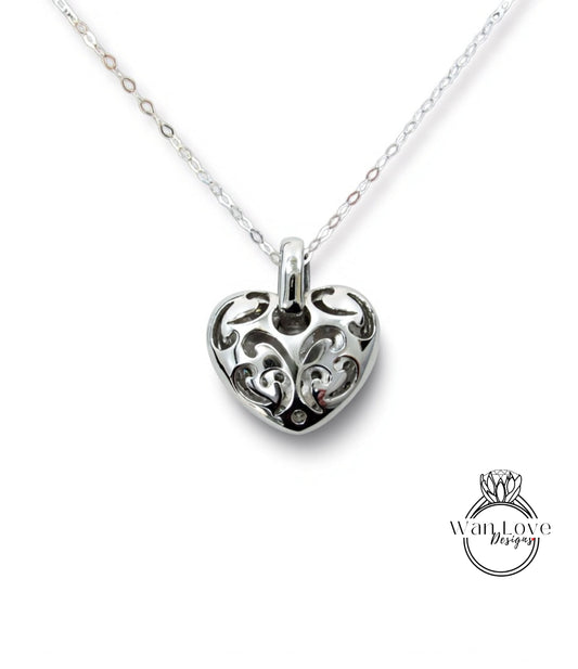 A silver heart-shaped pendant with an intricate floral design on a chain.