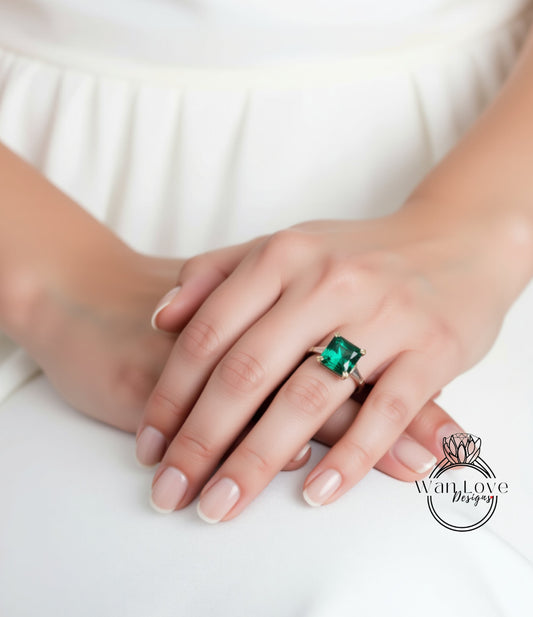 A close-up of a person's hand wearing a ring with a large, green gemstone.