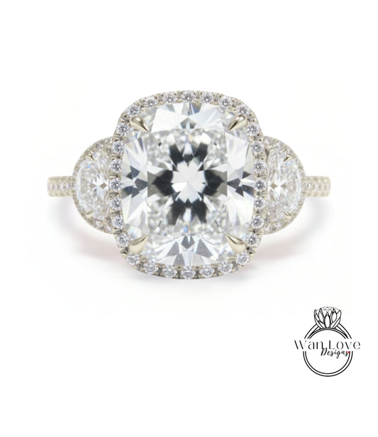 A stunning diamond engagement ring with a large central diamond surrounded by smaller diamonds on either side, set in a halo of smaller diamonds.