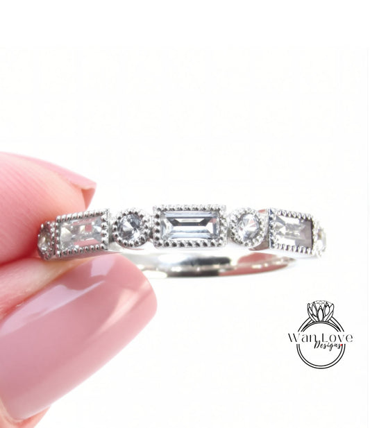 A close-up image of a person's hand holding a silver ring adorned with various gemstones.