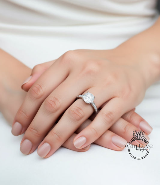 A close-up image of a person's hand wearing a diamond engagement ring.