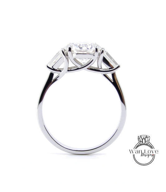 A silver engagement ring with a large central diamond surrounded by smaller diamonds on either side.