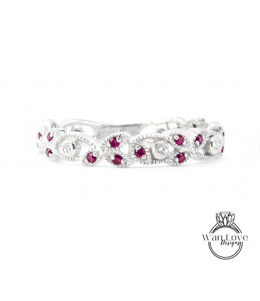 A silver ring with a decorative floral design and red gemstones.
