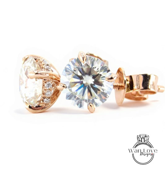 A close-up image of a pair of gold-toned earrings with a large, clear diamond set in the center.