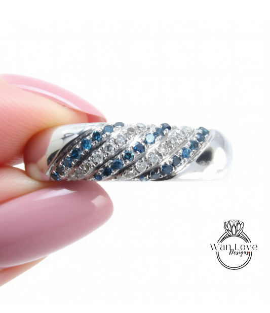 A hand holding a silver ring adorned with blue and white gemstones.