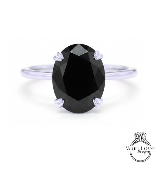 A close-up of a silver ring with a large, dark black diamond as the centerpiece.