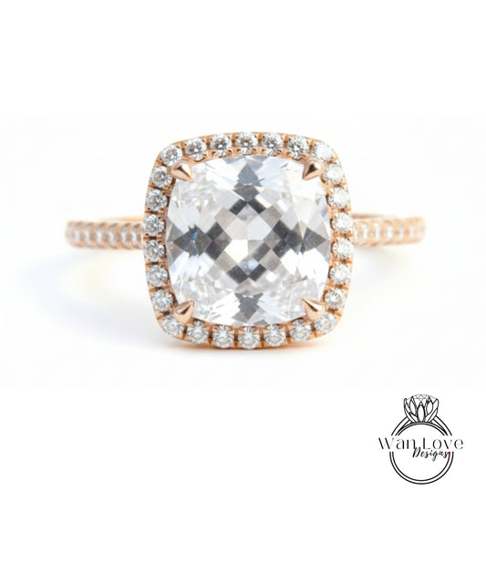 A large, clear gemstone ring with a halo of smaller diamonds around the center stone.