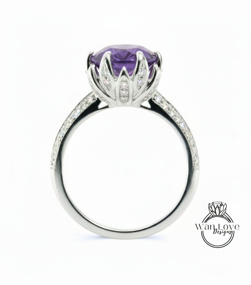 A silver ring with a large purple gemstone, likely an amethyst, at the center. The ring has a delicate flower-like design around the gemstone, and it is set with small diamonds.