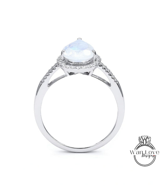 A silver engagement ring with a large moonstone set in a halo of smaller diamonds.