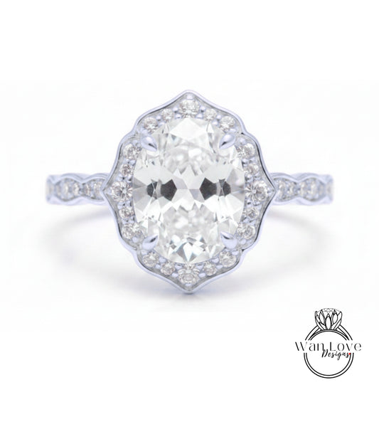 A close-up of a diamond engagement ring with a large oval-shaped diamond set in a halo of smaller diamonds.