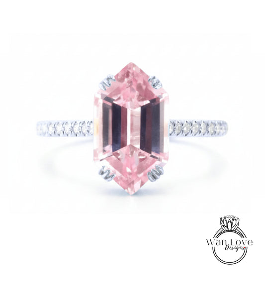 A pink gemstone engagement ring with a diamond band and a logo for "Wanted Love Designs" in the bottom right corner.