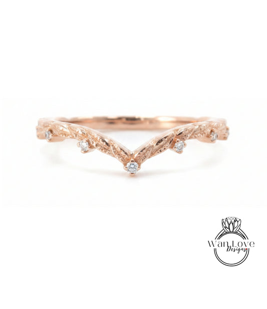 A rose gold ring with a v-shaped design and small diamonds set in the center.