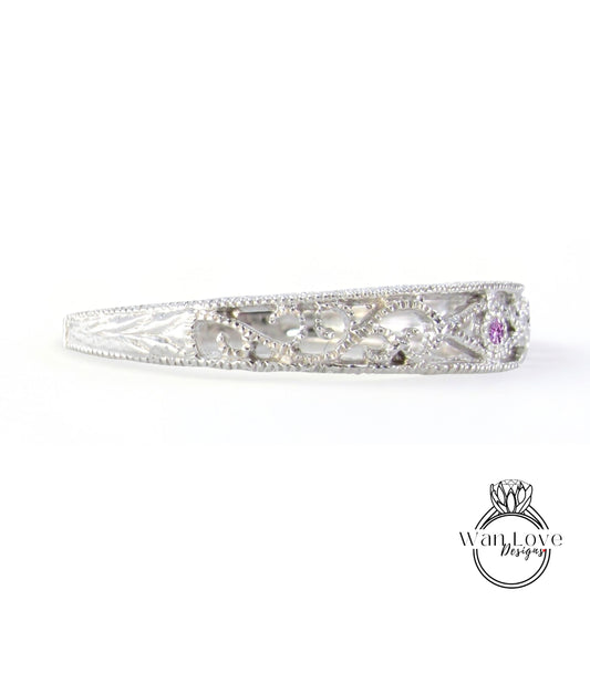 A silver bracelet with a decorative design and a small purple gemstone.