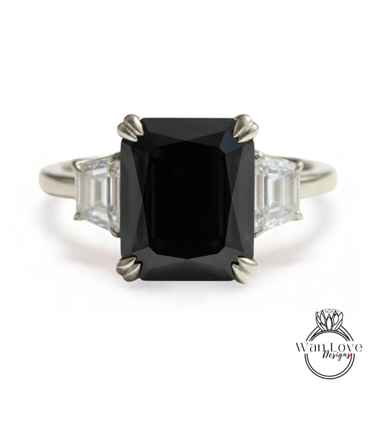 A silver ring with a large black diamond as the centerpiece, surrounded by smaller diamonds.