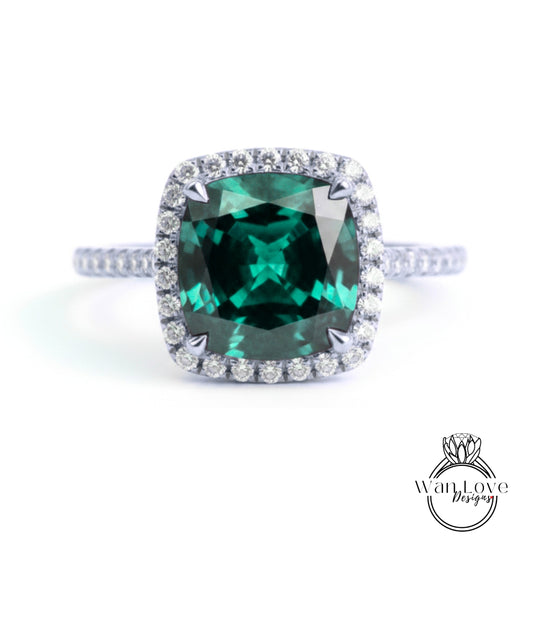 A stunning ring featuring a large, square-cut green gemstone surrounded by a halo of smaller diamonds set in a silver band.