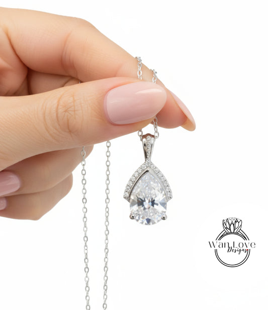 A hand holding a silver necklace with a large, clear diamond pendant.