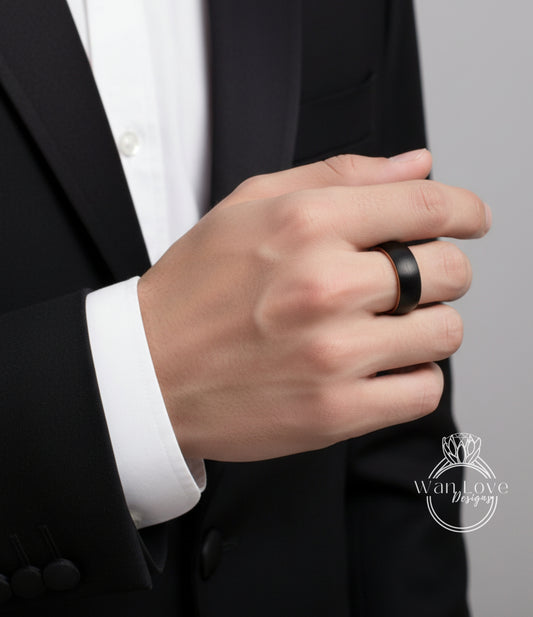 A close-up of a person's hand wearing a black ring, with a black suit jacket visible.