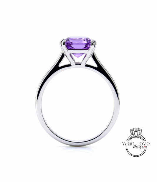 A silver engagement ring with a large, clear purple gemstone set in the center.