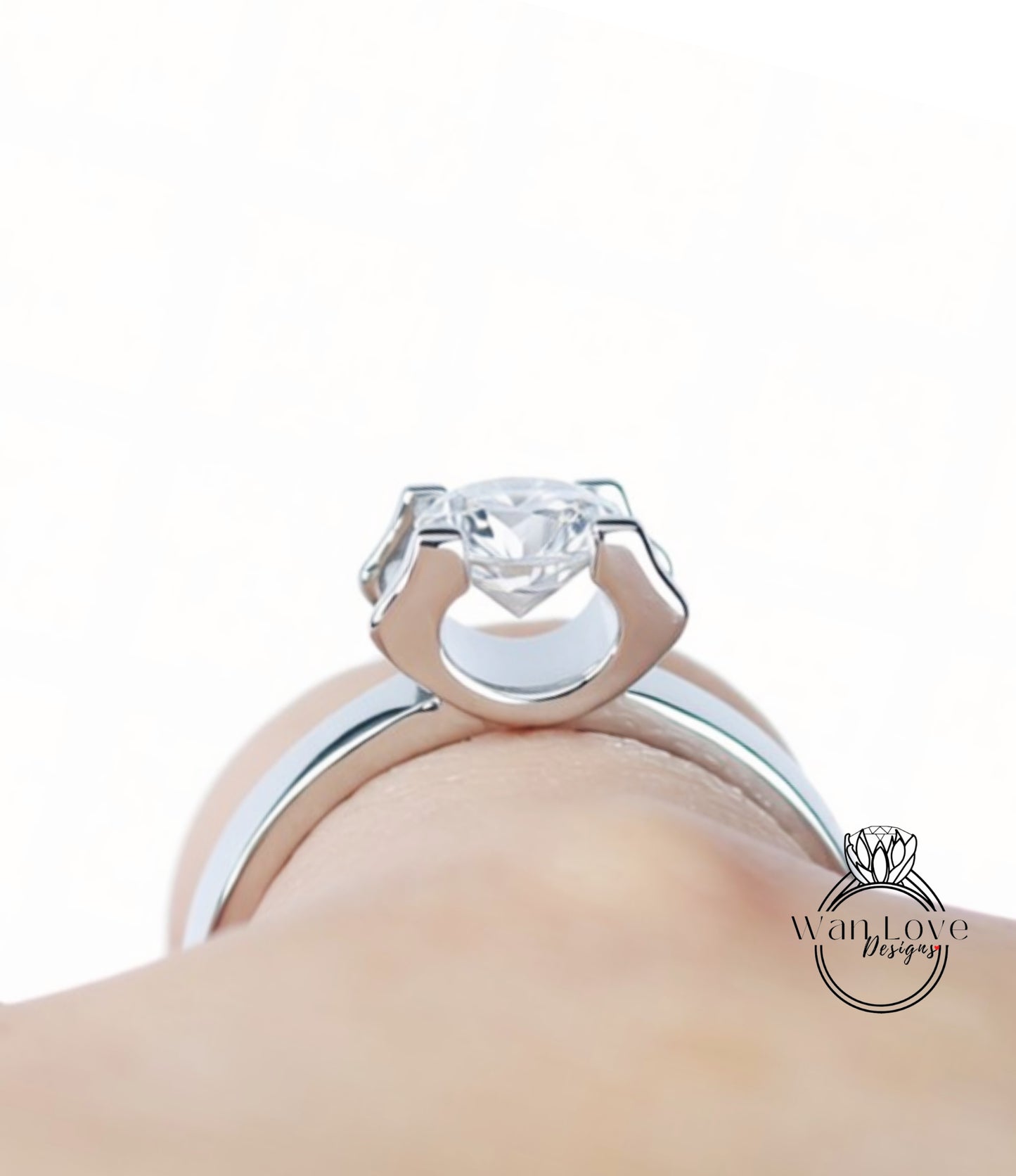 A close-up view of a person's hand wearing a silver ring with a large, clear gemstone.