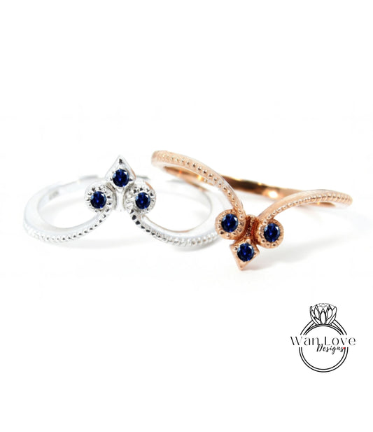 two rings with blue gemstones, one silver and one gold, set against a white background.