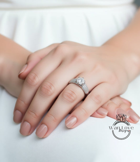 A close-up of a person's hand wearing a diamond engagement ring.
