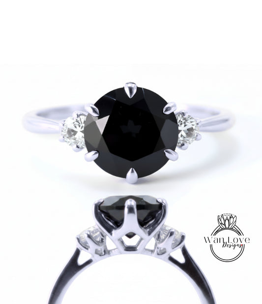 a silver ring with a large black diamond as the centerpiece. The ring has a unique design with three smaller diamonds on either side of the large black diamond.