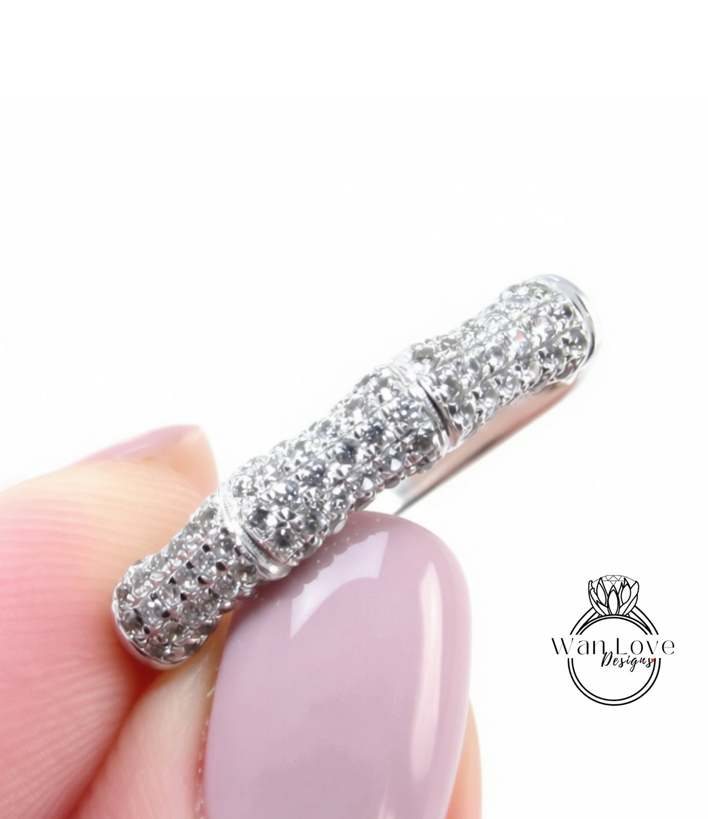 A close-up image of a person's hand holding a ring with a large, sparkling diamond band.