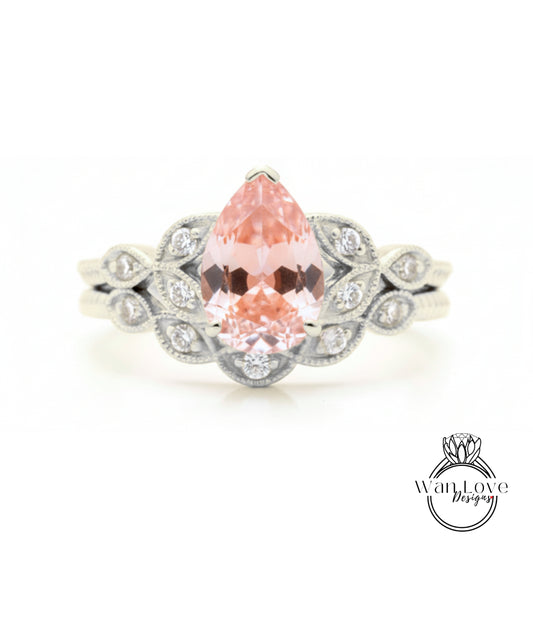 A close-up image of a silver ring with a large, pink gemstone at the center, surrounded by smaller diamonds.