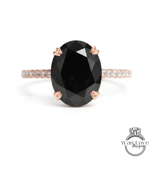 A large oval-shaped black diamond ring with a thin gold band and small diamonds around the band.