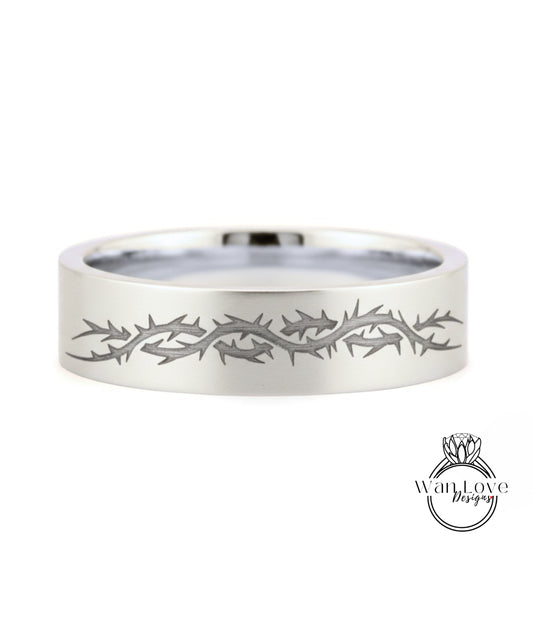 A silver ring with a design of thorns or spikes along its edge.