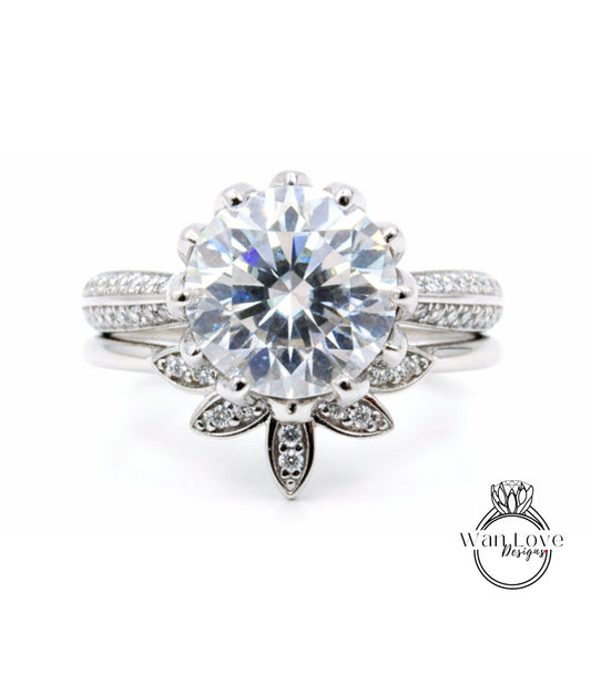 A stunning diamond engagement ring with a large central diamond surrounded by smaller diamonds on either side, set in a silver band with a leaf-shaped accent.