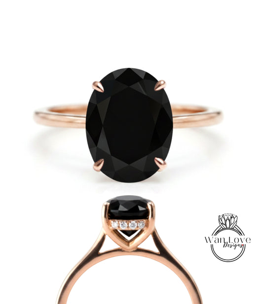 a rose gold ring with a large oval-shaped black gemstone, which appears to be a diamond.