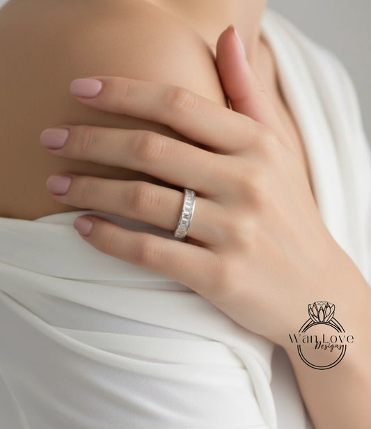 A close-up of a person's hand wearing a diamond ring, with a white blouse partially covering the hand.