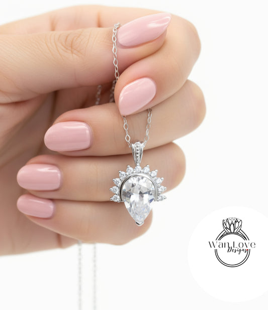 A hand holding a silver necklace with a large, clear gemstone pendant.