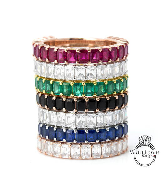 A stack of colorful rings with various gemstones, including diamonds and rubies, set in a gold band.
