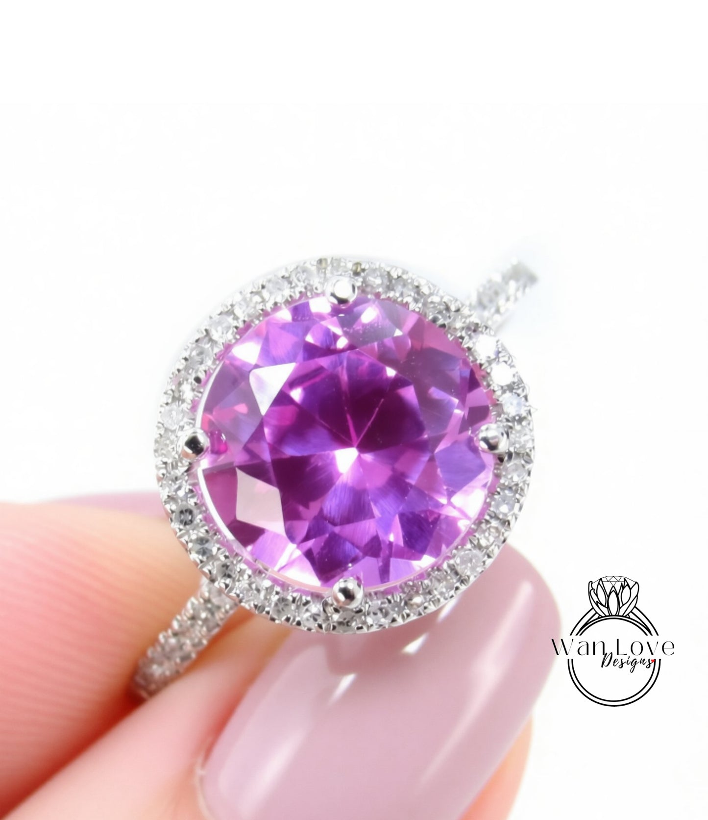 A close-up image of a person's hand holding a ring with a large, round, purple gemstone set in a halo of smaller diamonds.