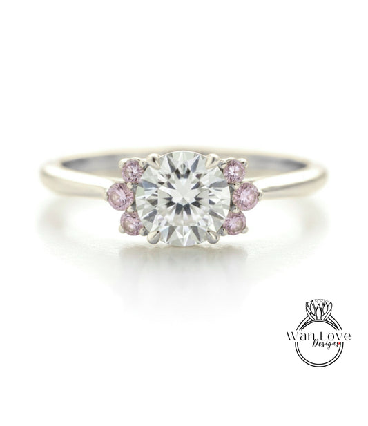 A close-up of a diamond engagement ring with a large central diamond surrounded by smaller diamonds and pink gemstones.