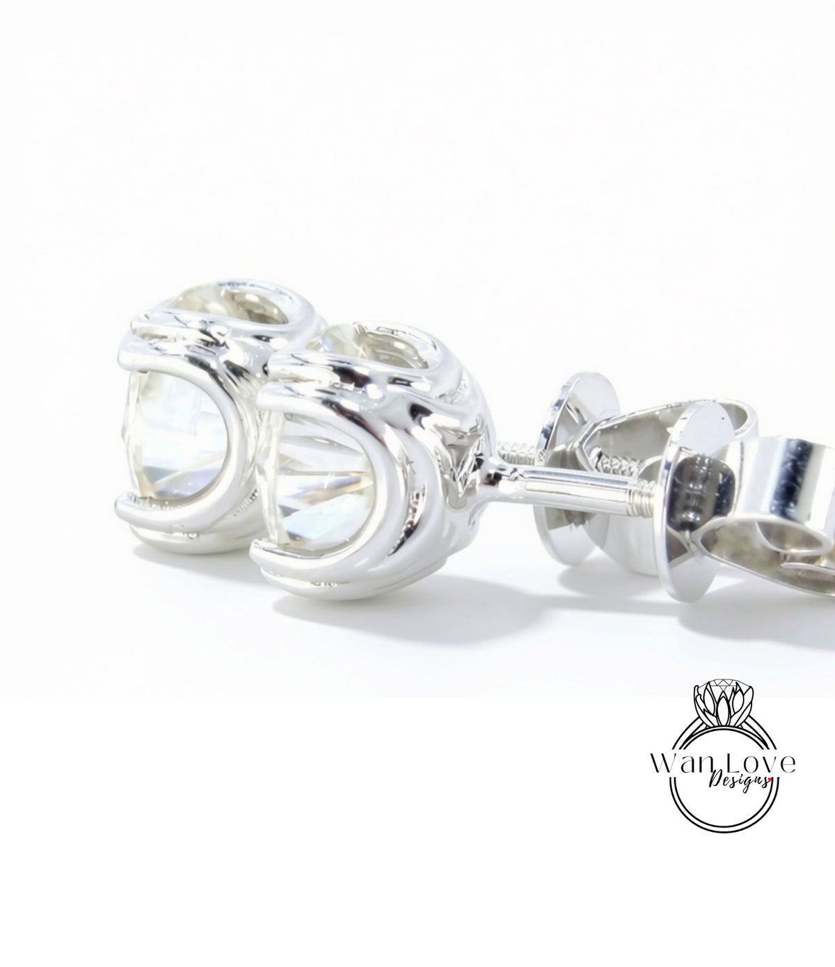 A pair of silver earrings with a clear gemstone, resting on a white surface.