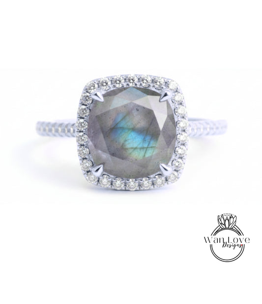 A silver ring with a large, blue-green gemstone at the center, surrounded by a halo of smaller diamonds.