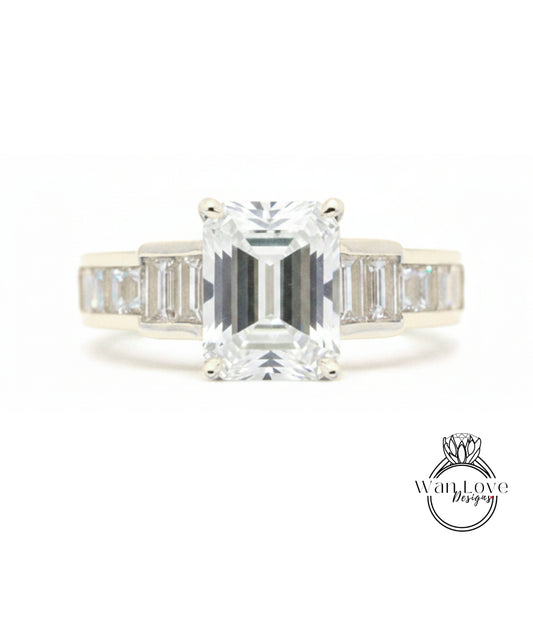 A diamond engagement ring with a large central diamond surrounded by smaller diamonds on either side.