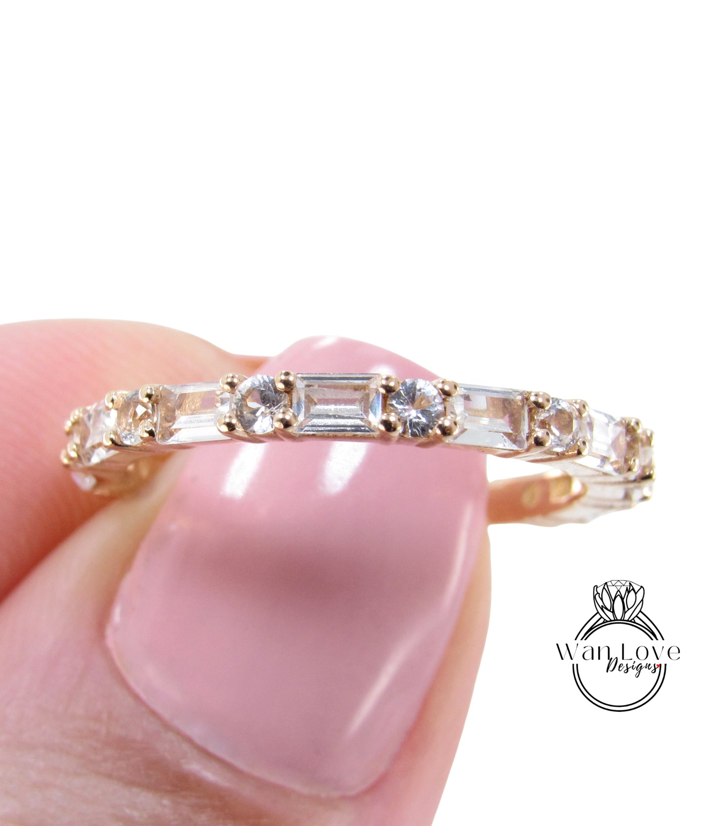 A close-up image of a person's hand holding a gold and clear gemstone ring with a row of clear gemstones.