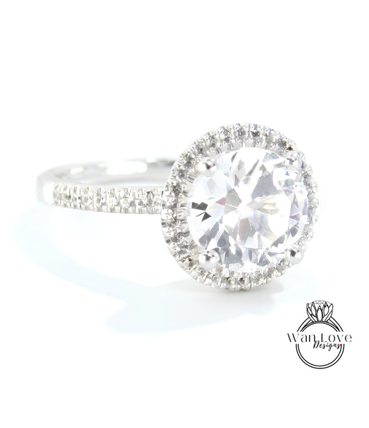 A close-up view of a diamond engagement ring with a large, round brilliant cut diamond set in a halo of smaller diamonds.