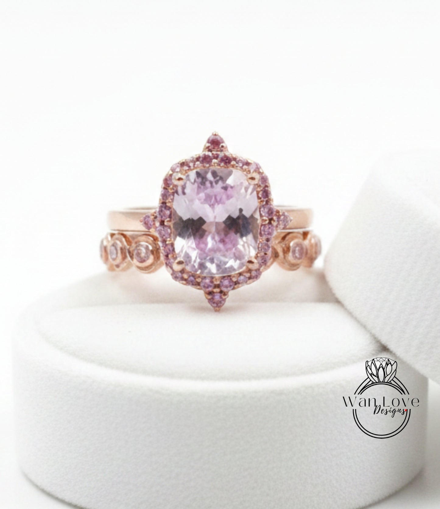 A pink gemstone ring with a large central stone surrounded by smaller stones and a halo of smaller stones on the sides.