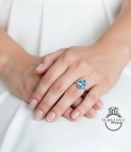 A close-up image of a person's hands wearing a ring with a blue gemstone.
