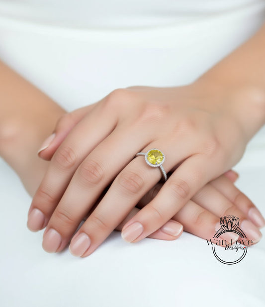 A close-up of a person's hands wearing a yellow gemstone ring on the ring finger.