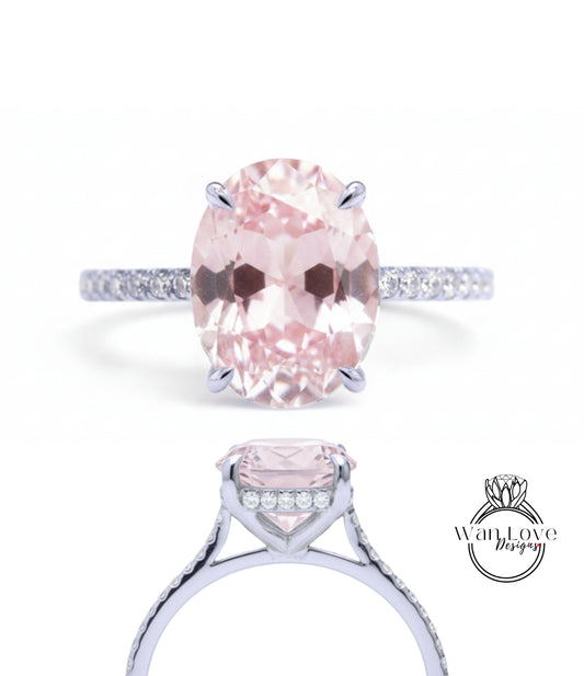 A close-up view of a diamond engagement ring with a large oval-shaped pink gemstone set in a silver band.