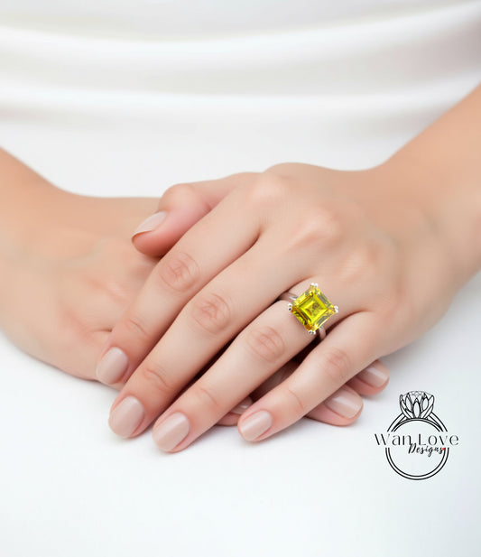 A close-up of a person's hand wearing a large yellow gemstone ring, resting on a white surface.