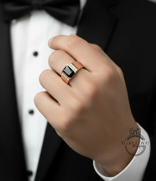 A close-up of a person's hand wearing a gold ring with a black gemstone, wearing a black tuxedo.