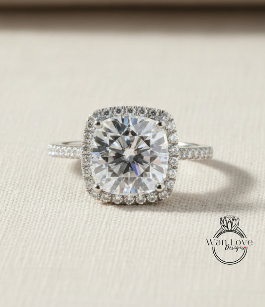 A large, brilliant-cut diamond engagement ring with a halo of smaller diamonds around the center stone, set in a silver band.