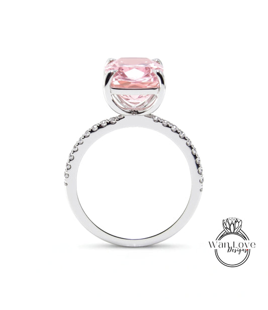 A silver ring with a large pink gemstone, likely a diamond, set in the center.